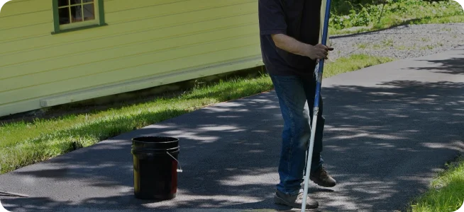 Crew member finishing a fresh concrete surface with a long-handled tool