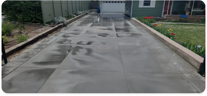 Freshly finished concrete driveway running alongside a house to the garage