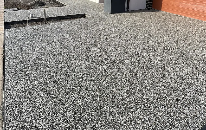 Exposed aggregate concrete driveway beside a modern home