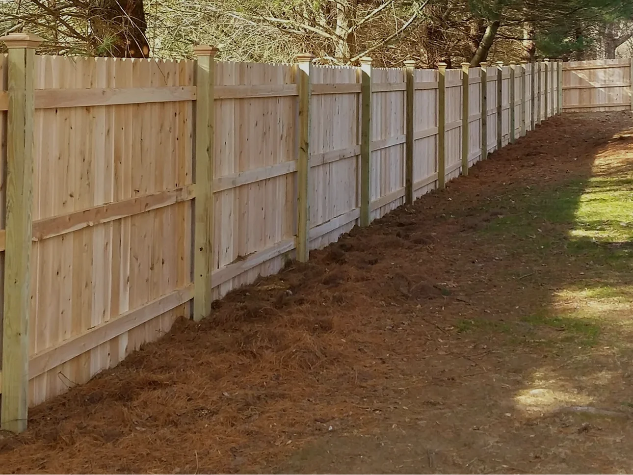 Horizontal slat hardwood privacy fence with uplighting beside a patio