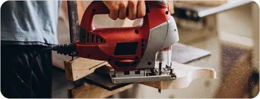 Jigsaw cutting through a timber board